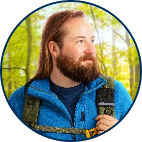 Right-facing profile of adult male hiker with backpack against forestland background